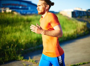 Portrait of young attractive sportsman with earphones running outside